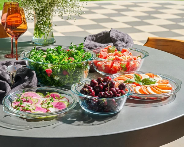 Conjunto de 3 caçarolas de vidro borossilicato transparente com tampas Le'raze sobre mesa de jardim.